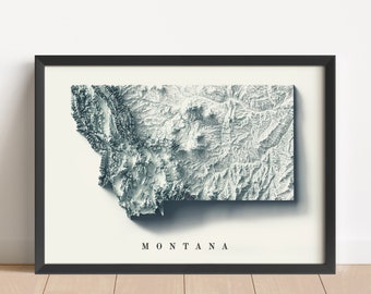 May include: A black framed print of a topographic map of Montana. The map is in shades of gray and white, with the state name "MONTANA" printed in black at the bottom.
