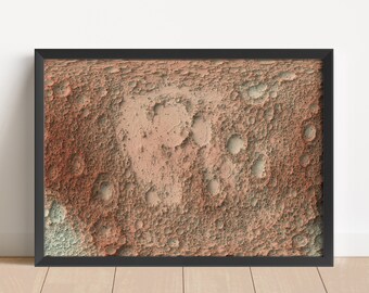 May include: A framed print of a close-up of a cratered surface, resembling the moon, with shades of orange, brown, and gray.