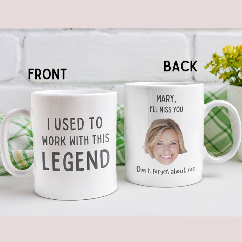 Op de afbeelding: Een witte keramische koffiemok met de tekst "I used to work with this legend" aan de voorkant en een foto van een vrouw met de tekst "Mary, I'll miss you. Don't forget about me..." aan de achterkant.