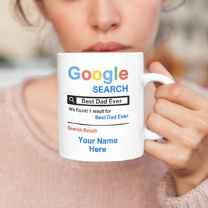 May include: White ceramic mug with a Google search bar graphic. The search bar says "Best Dad Ever" and the search results say "We found 1 result for Best Dad Ever". The search result is "Your Name Here".