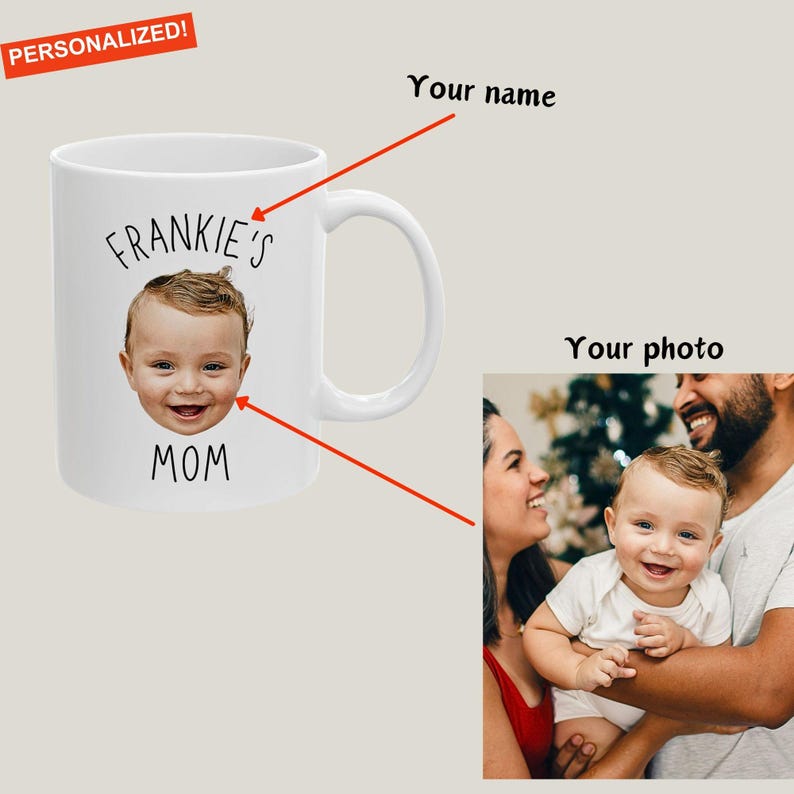 以下が含まれることがあります： 白いセラミックマグカップ、赤ちゃんのお顔と「FRANKIE'S MOM」の文字入り。左上の小さな赤いバナーには「PERSONALIZED！」と書かれています。右側には家族写真があります。