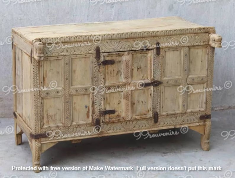 Puede incluir: Un armario de madera clara con tallas intrincadas y dos puertas. El armario tiene una forma rectangular y se asienta sobre cuatro patas. El armario est&aacute; hecho de madera y tiene un acabado marr&oacute;n claro.