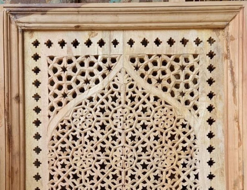 May include: A wooden panel with intricate carved geometric designs in a light wood tone. The design features a repeating pattern of stars and circles.
