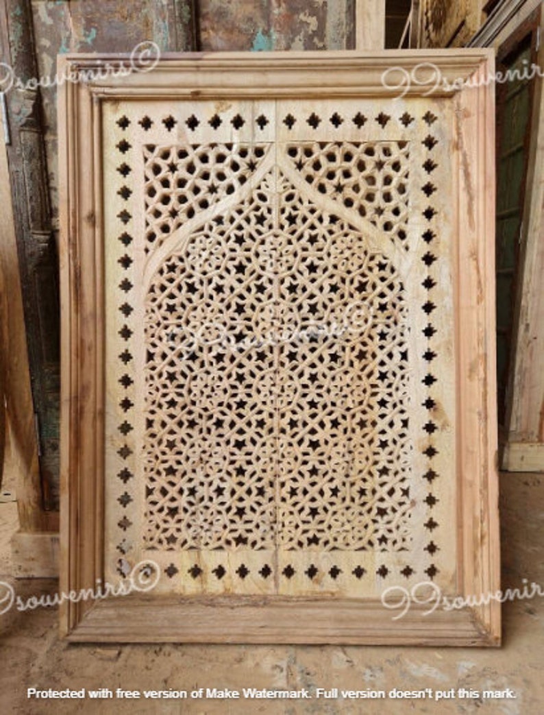 May include: A wooden windowpane with a carved geometric design. The design features a repeating pattern of stars and circles, creating a delicate and intricate look. The windowpane is framed in a simple wooden frame.