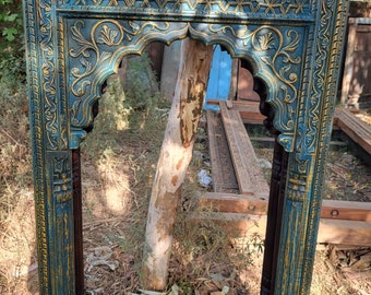 May include: A teal blue and gold wooden frame with intricate carvings. The frame has a traditional arch design and is perfect for a mirror or artwork.