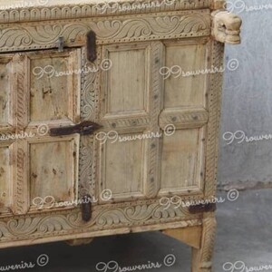 Puede incluir: Un armario de madera tallada con un acabado marr&oacute;n claro. El armario tiene un dise&ntilde;o decorativo con tallas intrincadas y una puerta con bisagras. El armario tiene cuatro patas y est&aacute; hecho de madera.