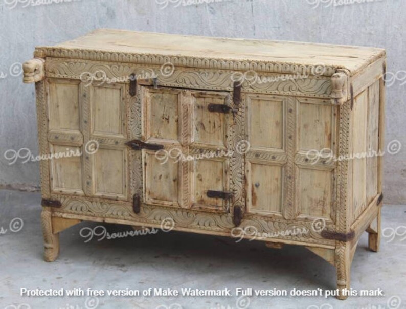 Puede incluir: Un cofre de madera blanco con intrincados tallados y una sola puerta. El cofre tiene una forma rectangular y se asienta sobre cuatro patas. El cofre est&aacute; hecho de madera clara y tiene un acabado desgastado.