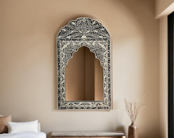May include: A black and white arched mirror with an intricate floral design. The mirror is framed with a decorative border of white floral motifs on a black background.