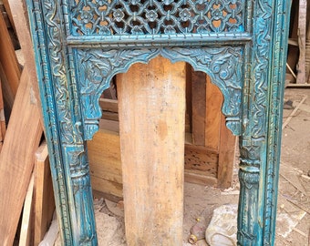May include: A teal blue wooden frame with intricate carvings and a lattice design. The frame has a traditional arch shape and is perfect for a mirror or artwork.