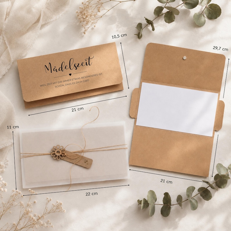 May include: A set of brown kraft paper envelopes and cards with black text reading M&auml;delszeit, Weil Zeit mit dir immer etwas Besonderes ist, Sch&ouml;n, dass es dich gibt. Includes a translucent vellum sleeve tied with twine and a wooden flower charm, with dimensions labelled in centimetres.