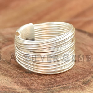 May include: A silver ring with multiple thin bands wrapped around each other. The ring is made of sterling silver and has a polished finish.
