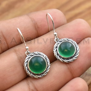 May include: A pair of silver earrings with green gemstone cabochons. The earrings have a twisted rope design around the stones.