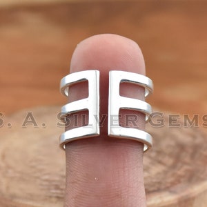 May include: A silver ring with a geometric design. The ring is made of three bands that are connected together. The bands are open on one side, allowing the ring to be adjusted to fit different finger sizes.