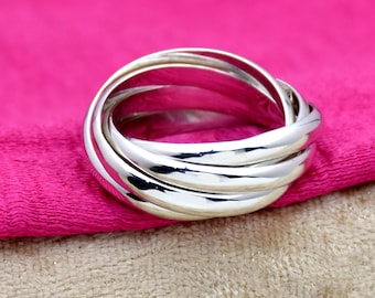Könnte beinhalten: Ein silberner Ring mit vier ineinandergreifenden Bändern. Der Ring ist glatt und glänzend.