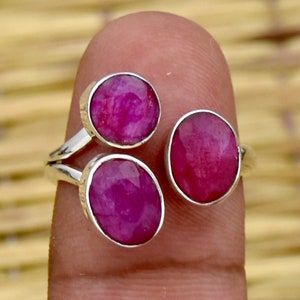 Könnte beinhalten: Ein silberner Ring mit drei rosafarbenen ovalen Edelsteinen. Der Ring befindet sich an einem Finger.