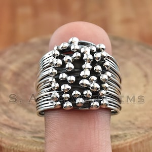 Puede incluir: Anillo de plata con un diseño texturizado de pequeñas bolas. El anillo es ancho y tiene un aspecto apilado.