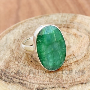 Könnte beinhalten: Ein Silberring mit einem großen, ovalen, grünen Edelstein. Der Edelstein hat eine strukturierte, fast kristalline Oberfläche.