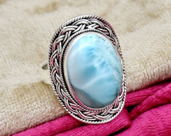 May include: A silver ring with a blue and white oval cabochon gemstone set in a braided design.