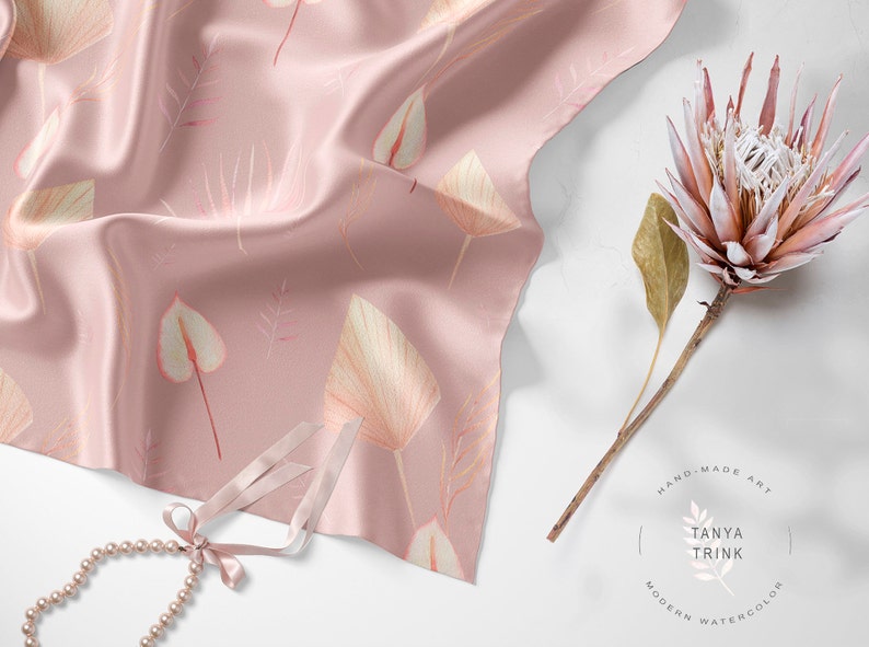 May include: A pink silk scarf with a delicate floral pattern featuring leaves and flowers. The scarf is draped over a white surface with a pearl necklace and a dried protea flower.