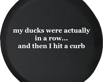 May include: Black spare tyre cover with white text. The text reads "my ducks were actually in a row... and then I hit a curb."