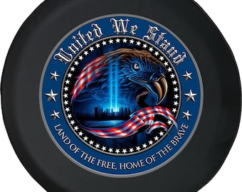 May include: Black spare wheel cover with a patriotic design. The central image features an eagle, the American flag, and the text "United We Stand, Land of the Free, Home of the Brave" within a blue circular border.