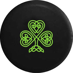 May include: A black circular object featuring a bright green Celtic knot shamrock design. The shamrock is composed of three heart-shaped leaves, with intricate knotwork details. The design is centered on the black background.