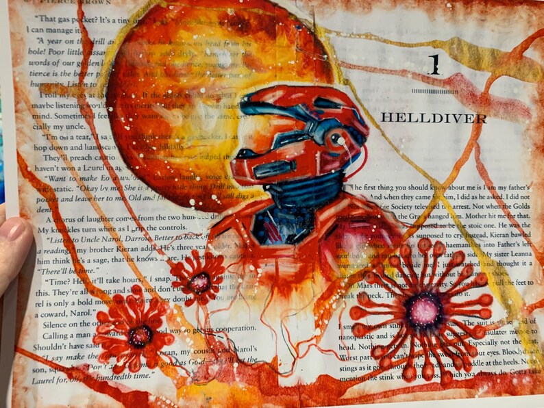 May include: An illustration on a book page featuring a red armored figure in a helmet, a large orange planet, and red floral motifs. The text "1 HELLDIVER" is printed at the top right. The artwork uses red, orange, and yellow watercolor washes.
