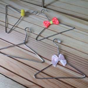 May include: Four silver wire hangers with different colored bows. The bows are pink, orange, yellow, and white.