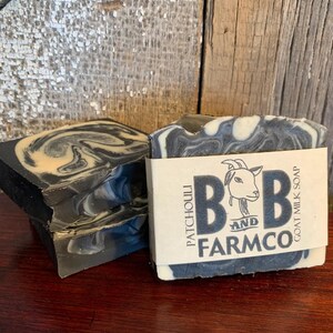 May include: Three bars of black and white marbled goat milk soap with a label that reads "Patchouli and Farmco Goat Milk Soap".