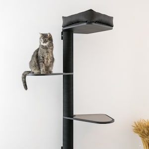 May include: A black cat tree with three platforms and a bed. The cat tree is mounted to a white wall. The cat tree is made of wood and has a black fabric covering. The cat tree is 7 feet tall.