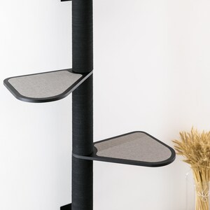 May include: A black wall-mounted cat tree with three platforms. The platforms are covered in gray fabric and are shaped like a triangle. The cat tree is made of a sturdy material and is designed to be durable.