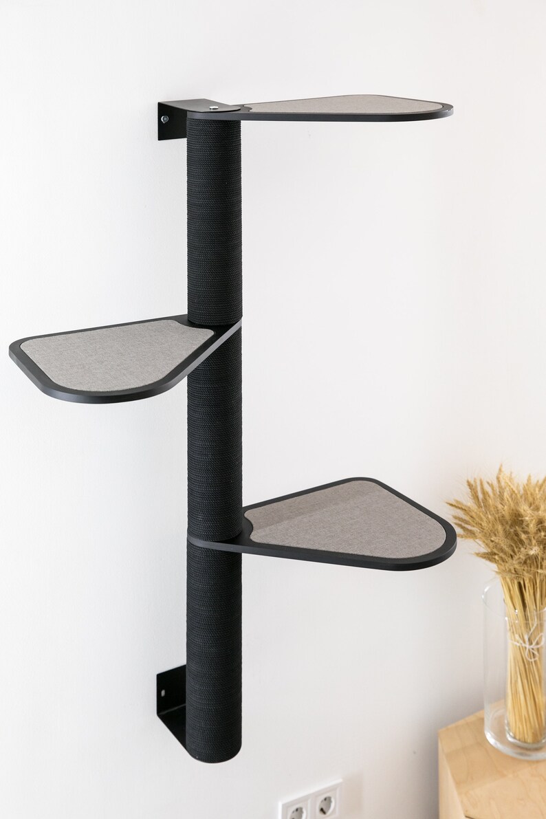 May include: A black wall-mounted cat tree with three platforms. The platforms are covered in gray fabric and are shaped like a triangle. The cat tree is made of a sturdy material and is designed to be durable.