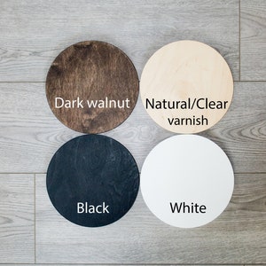Puede incluir: Cuatro c&iacute;rculos de madera en diferentes colores: nogal oscuro, barniz natural/transparente, negro y blanco. Los c&iacute;rculos est&aacute;n dispuestos en un patr&oacute;n cuadrado sobre una superficie de madera.