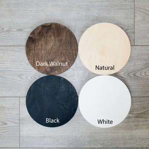 May include: Four round wooden discs in different colours: dark walnut, natural, black, and white. The discs are arranged in a square pattern on a wooden floor.