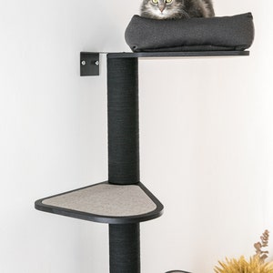 May include: A black cat tree with a gray cat sitting on the top platform. The cat tree has three platforms and a scratching post. The platforms are covered in a gray fabric.