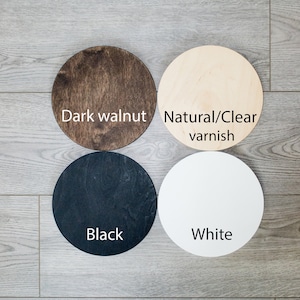 Pu&ograve; includere: Quattro cerchi di legno in diversi colori: noce scuro, vernice naturale/trasparente, nero e bianco. I cerchi sono disposti in uno schema quadrato su una superficie di legno.