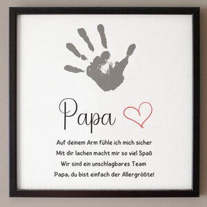May include: Framed print with a gray handprint, the word "Papa", and a red heart. Below, text in black script reads, "On your arm I feel safe, laughing with you is so much fun, we are an unbeatable team, Papa, you are simply the greatest!"