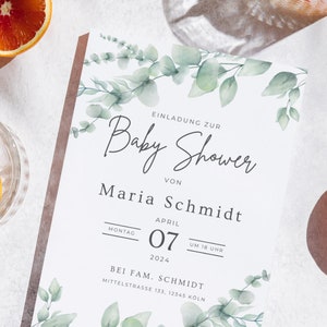 May include: A baby shower invitation with a watercolor eucalyptus leaf design. The invitation includes the text "Baby Shower" and details for Maria Schmidt's baby shower on April 7, 2024, at 6 PM. The invitation is on a white background.
