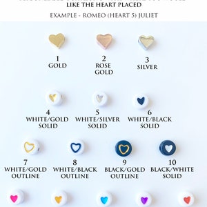 May include: A chart showing 15 different heart-shaped charms for jewelry making. The charms are in various colors, including gold, silver, white, black, pink, yellow, blue, purple, and red. Each charm has a number from 1 to 15, and a description of the color and design. The text "WANT TO ADD A LOVE HEART?" is at the top of the chart. The text "SIMPLY INCLUDE THE HEART NUMBER IN THE PERSONLIASED BOX ALONG WITH WHERE YOU WOULD LIKE THE HEART PLACED" is below the title. The text "EXAMPLE - ROMEO (HEART 5) JULIET" is below the instructions.