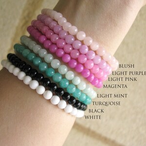May include: A stack of colorful beaded bracelets in blush, light purple, light pink, magenta, light mint, turquoise, black, and white.