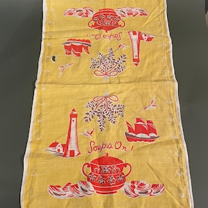 May include: A yellow tea towel with a red and white design. The design features a lighthouse, a boat, a pot of soup, and the text "Soup's On!"