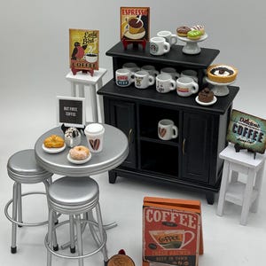 May include: Miniature coffee shop scene with a black cabinet, silver stools, and a round table. Includes coffee cups, pastries, and signs that read "Early Bird Coffee," "Espresso," and "But First Coffee." A penny is displayed.