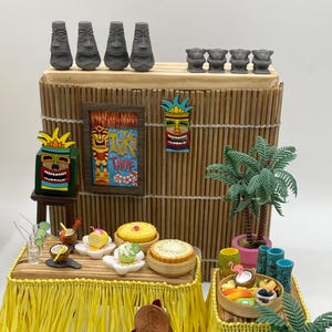 Puede incluir: Una escena de bar tiki en miniatura con un techo de paja amarillo, una barra de madera con una falda de hula amarilla, dos palmeras y un letrero que dice "Tiki Time".