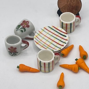 May include: Miniature ceramic tea set with two floral-decorated cups, two striped cups, a striped plate, and several orange carrot miniatures. A penny is included for scale. Perfect for dollhouses or craft projects.