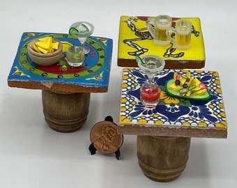 May include: Three miniature tables with colorful tile tops and wooden barrel bases. Each table is decorated with miniature food and drinks, including a margarita, beer, and a plate of nachos.