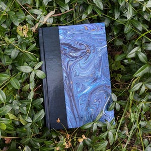 May include: A blue and black marbled hardcover book with a black spine.