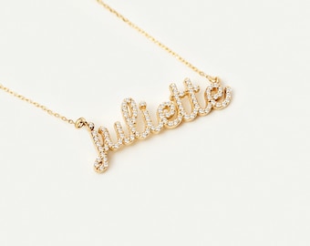 May include: A gold necklace with the name "Juliette" spelled out in cursive script. The letters are outlined with small, clear gemstones.