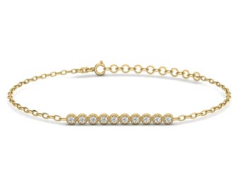 May include: A yellow gold chain bracelet featuring a horizontal bar of ten small, round, clear stones set in individual gold bezels with a milgrain edge. The bracelet includes a delicate link chain and a circular spring ring clasp closure.