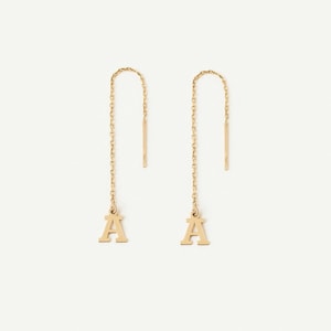 May include: A pair of gold-toned threader earrings, each featuring a delicate fine chain that suspends a capital letter A charm. The design includes a straight post at the top of the chain, allowing the earring to be pulled through the earlobe.
