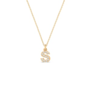 May include: A gold necklace featuring a delicate chain and a small pendant in the shape of the letter S. The letter S pendant is embellished with small, clear, sparkling stones set along its surface, creating a bright and reflective appearance.